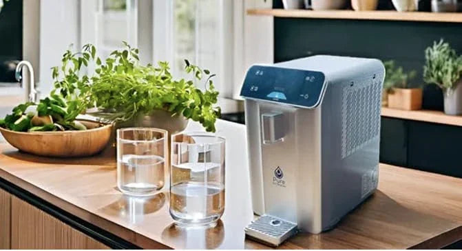 Atmospheric Water Generator on a kitchen counter with glasses of water and plants.