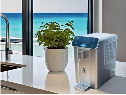 An atmospheric water generator on a kitchen counter with a plant and ocean view in the background